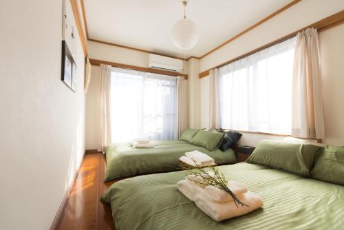 东京K&K Apartment Kita-Akabane #301的一间卧室设有两张绿色的床和两个窗户。