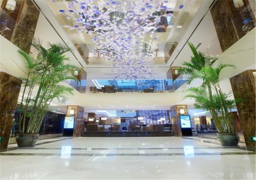厦门厦门航空金雁酒店（全新室内无边泳池）的大堂,在大楼内,有吊灯和棕榈树