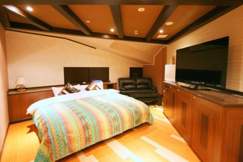 DaitōSari Resort Daito (Adult only)的一间卧室配有一张床和一台平面电视