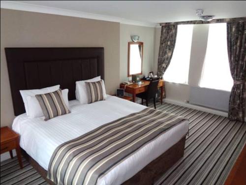 德比阿斯顿柯特酒店的酒店客房设有一张大床和一张书桌。