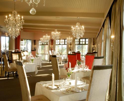 温特和克海因茨伯格酒店的一间设有白色桌子和吊灯的用餐室