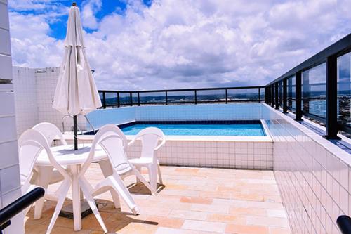 累西腓Apartamento - Ed Jatiuca的阳台设有游泳池、椅子和遮阳伞。