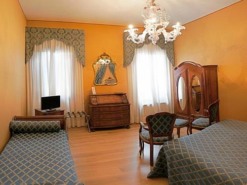 威尼斯坎达运河酒店的一间卧室配有一张床、一张书桌和一个吊灯。