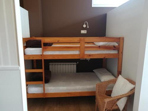 阿尔苏阿Albergue Ultreia的小型客房配有两张双层床和椅子。