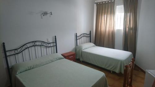 马塔拉斯卡尼亚斯塔玛琳多旅馆的一间卧室设有两张床,窗户配有窗帘