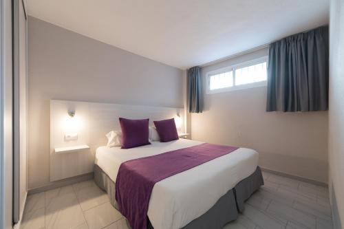 英格兰海滩埃奥拉斯加西拉斯公寓式酒店的一间卧室配有一张带紫色枕头的大床