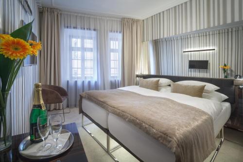 布拉格克雷门庭酒店的一间卧室配有一张床和一张桌子及一瓶香槟