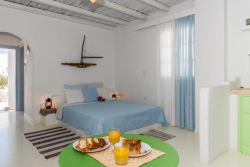阿达玛斯Thalassitra Village Hotel的一间白色的卧室,配有一张床和一张桌子,上面有食物