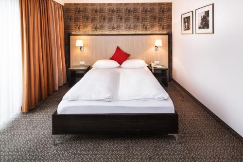 杜伊斯堡广场酒店 的一间卧室配有一张带红色枕头的大床