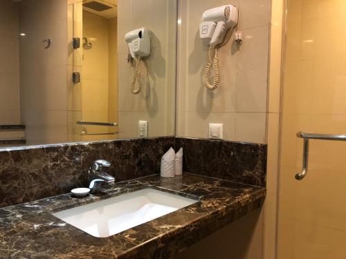 棉兰樱花大酒店的一间带水槽的浴室和墙上的两部电话
