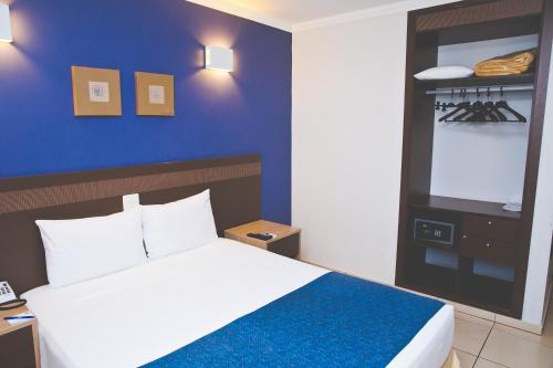 阿拉拉夸拉阿拉拉夸拉康福特酒店的一间卧室设有一张床和蓝色的墙壁