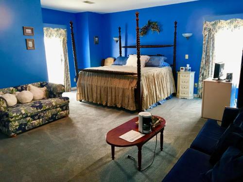 VersaillesRabbit Creek Bed & Breakfast的一间拥有蓝色墙壁的卧室,配有一张床和一张桌子