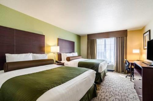 文顿Cobblestone Inn & Suites - Vinton, LA的酒店客房设有两张床和电视。
