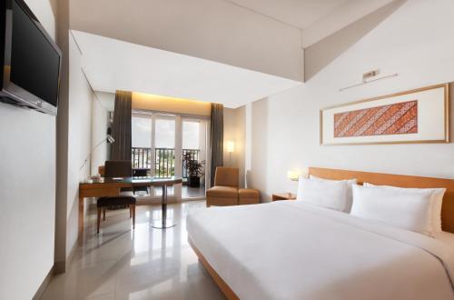 泗水The Capital Hotel Surabaya的配有一张床和一张书桌的酒店客房