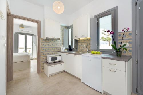 梅加洛克里白色和谐套房公寓的厨房配有白色橱柜和微波炉