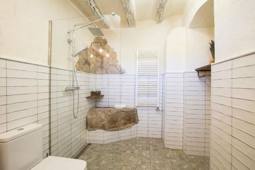 拉塞尔瓦德尔坎普Mas del Sord 1335的白色瓷砖浴室设有卫生间和岩石。