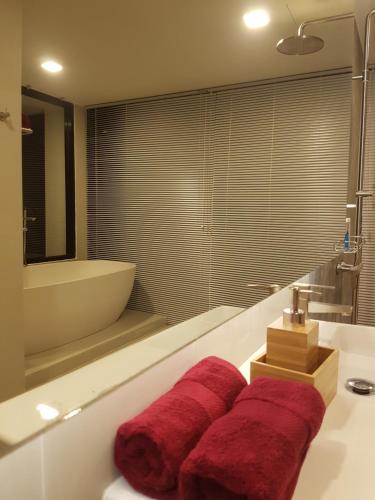 波湾8IK88 Resort - SHA Extra Plus的浴室配有浴缸和带红色毛巾的盥洗盆。
