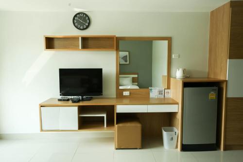北柳JK LIVING Hotel And Service Apartment的客房设有一张带电视和时钟的书桌。