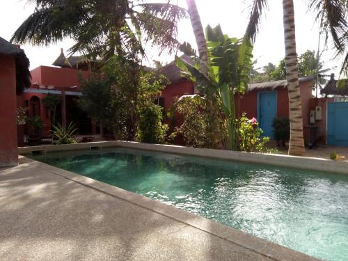 Joal-FadioutHôtel Joal Lodge的棕榈树屋前的游泳池