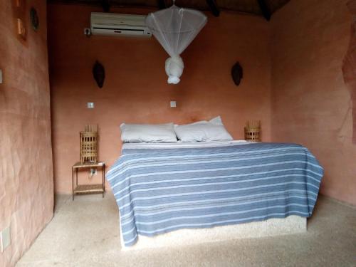 Joal-FadioutHôtel Joal Lodge的一间卧室配有一张带蓝白条纹毯子的床
