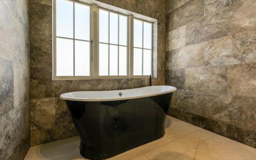 欧尼罗亚The Lodge at Mudbrick的带浴缸的浴室和窗户