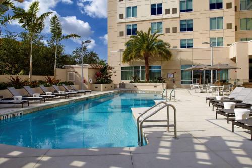 迈阿密迈阿密机场东凯悦嘉轩酒店的一座带躺椅的酒店游泳池以及一座建筑