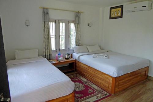 索拉哈Tharu Mahal的客房设有两张床、一张桌子和一个窗户。