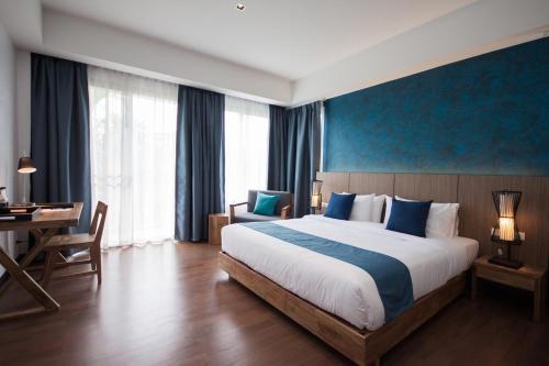 芭堤雅市中心The Leela Resort & Spa Pattaya的酒店客房设有一张大床和一张书桌。