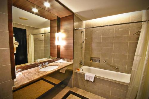 波德申Thistle Port Dickson Resort的浴室配有盥洗盆、浴缸和镜子
