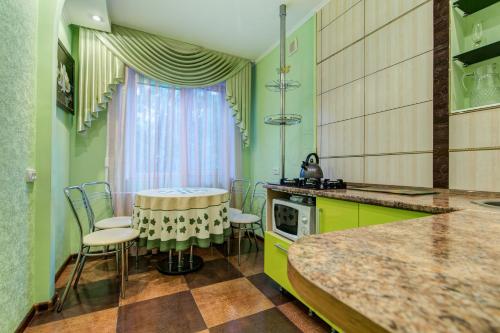 第聂伯罗Apartment on Riverfront of Dnepr的厨房配有绿色橱柜和桌椅