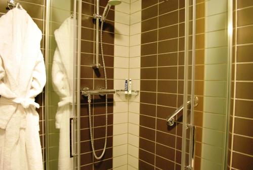 萨沃纳加萨沃纳酒店的浴室铺有棕色和绿色瓷砖,设有淋浴。