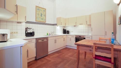 WalkendorfFerienGut Dalwitz Gutshaus的厨房配有白色橱柜和木桌