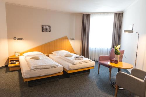 Tröstau法衡巴高尔夫酒店的酒店客房,配有两张床和椅子