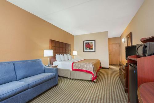 威斯特维尔Ramada by Wyndham Columbus North的酒店客房,配有床和沙发