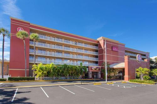 坦帕Ramada by Wyndham Tampa Westshore Airport South的停车场内一座棕榈树的大型红色建筑