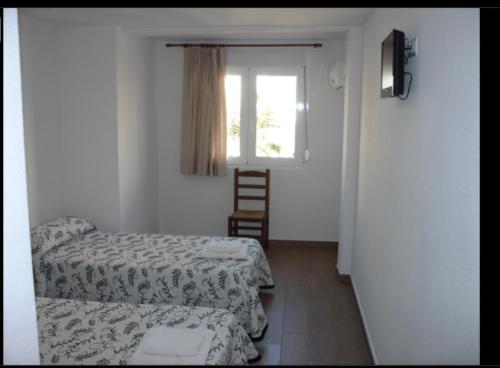 翁蒂年特Habitacions Casa Roberto的小房间设有两张床和窗户