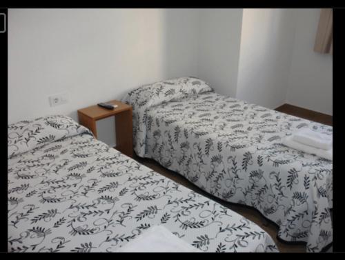 翁蒂年特Habitacions Casa Roberto的客房设有两张床和一张带床罩的桌子。