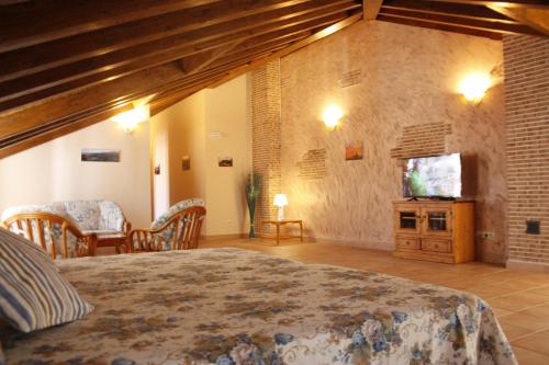 瓜达利斯-德拉谢拉Casa Rural La Fragua的一间卧室配有一张床,并在一间客房内配有电视。