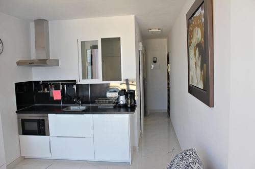 卡尔佩Apartamento Horizonte的厨房配有白色橱柜和黑色台面
