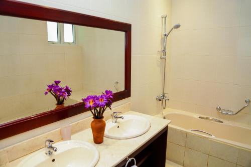 本托塔本托塔水滨度假酒店的浴室设有两个水槽和一面紫色花卉镜子