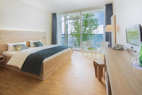 森夫滕贝格森夫滕贝格湖海滩酒店的一间卧室配有一张大床和电视