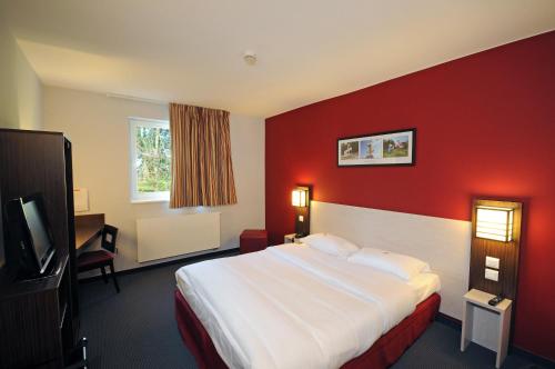 沙勒罗瓦DC Hotel Charleroi Airport的酒店客房,设有床铺和红色的墙壁