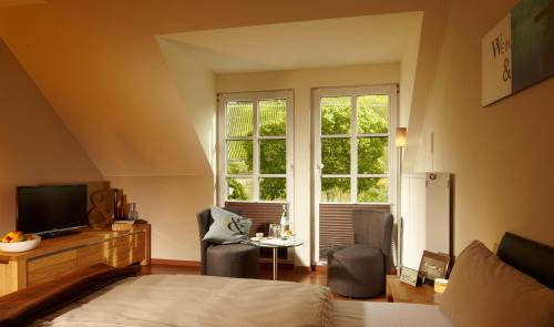 特里滕海姆Wein- & Tafelhaus的一间卧室配有一张床、两把椅子和电视