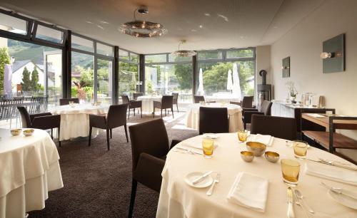 特里滕海姆Wein- & Tafelhaus的餐厅设有白色的桌椅和大窗户。