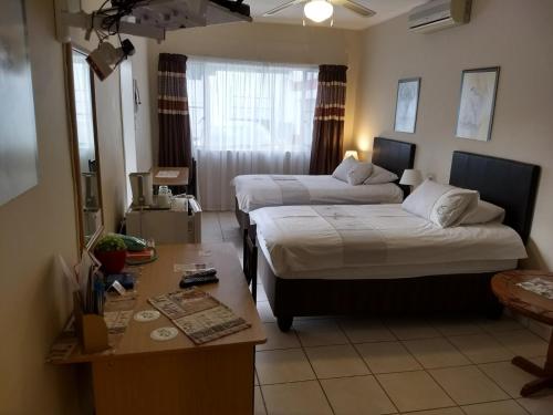 温特和克Tourmaline Guest House的酒店客房配有两张床和一张书桌