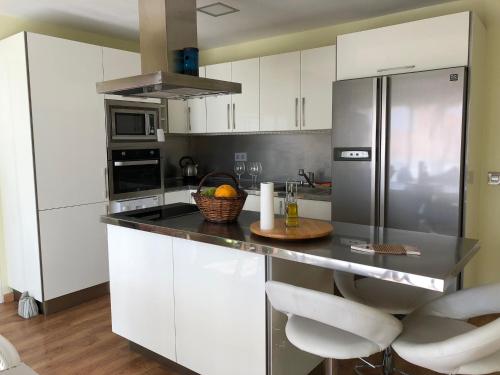 厄尔梅达诺Modern penthouse near the sea的厨房配有白色橱柜和不锈钢冰箱