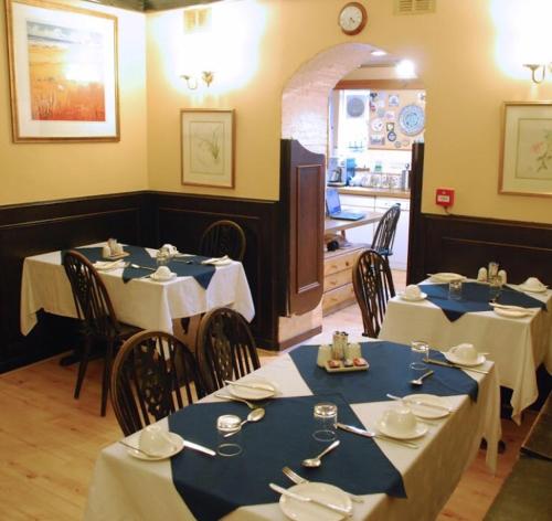 阿伯丁Denmore Guest House的一间设有两张桌子的用餐室,配有蓝色和白色的桌子