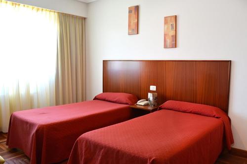 Pereiro de AguiarHotel Os Caracoles的两张位于酒店客房的床铺,配有红色床单