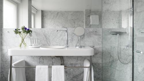 斯德哥尔摩Nobis Hotel Stockholm, a Member of Design Hotels™的白色的浴室设有水槽和淋浴。