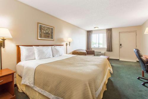 梅萨Travel Inn - Mesa的酒店客房带一张大床和一把椅子